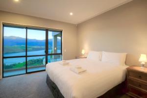 - une chambre avec un grand lit blanc et une grande fenêtre dans l'établissement Lake Hayes Luxury Residence, à Queenstown