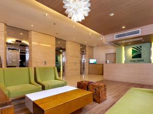 una hall con sedie verdi, tavolo e lampadario a braccio di Injap Tower Hotel a Città di Iloilo