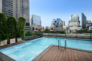 a swimming pool on the roof of a building with a city skyline at Arawana Regency Park Sukhumvit in Bangkok