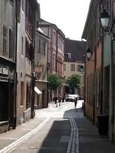 an empty street with buildings and people walking down the street at Studio Maison Verte Colmar Centre in Colmar