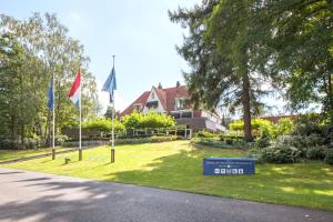 une maison avec drapeaux et panneau dans l'herbe dans l'établissement Fletcher Hotel Restaurant Sallandse Heuvelrug, à Rijssen