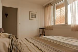 een slaapkamer met een bed, een raam en een stoel bij Moderne et Lumineux in Parijs