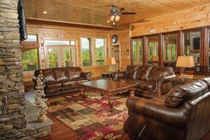 a living room with leather couches and a table at Foxwood Mansion Cabin in Pittman Center +47 photos