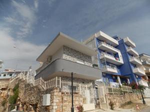 un bâtiment bleu avec des personnes assises sur les balcons dans l'établissement Vasili Apartments, à Saranda