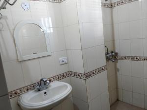 a white bathroom with a sink and a mirror at Hotel Empire in Guwahati