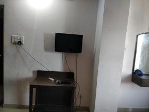 Habitación con mesa y TV en la pared. en Hotel Empire, en Guwahati