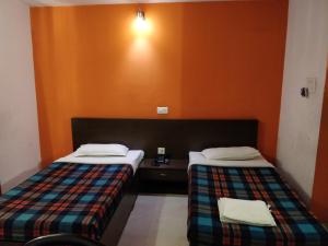 2 camas en una habitación con paredes de color naranja en Hotel Empire, en Guwahati
