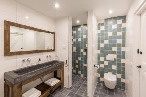 a bathroom with a sink and a toilet and a mirror at Welcome in - Vakantiehuis - Lepelstraat 18A 't Blauwtje in Vrouwenpolder +48 photos