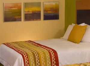 a bed in a room with three paintings on the wall at TownePlace Suites by Marriott Aiken Whiskey Road in Aiken