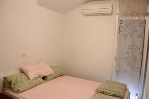 ein kleines Schlafzimmer mit einem Bett mit einem rosa Kissen in der Unterkunft Apartmani Vrsi Mulo in Vrsi
