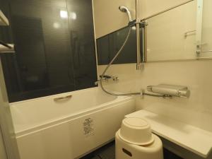 a bathroom with a tub and a toilet and a mirror at Haneda Inn in Tokyo