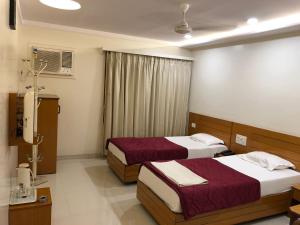 a hotel room with two beds and a window at Hotel Sarita in Surat