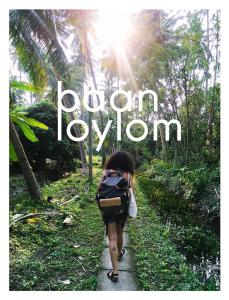 a woman walking down a path with the words demon joyon at Baan Loylom Farmstay in Amphawa