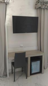 a desk with a chair and a television on a wall at Hotel Aurora in Porto Cesareo
