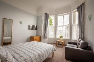 1 dormitorio con cama, sofá y ventana en Clydesdale Apartments en Torquay