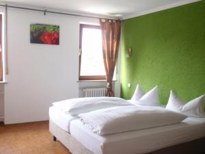 um quarto com uma cama branca e uma parede verde em Weinhotel Goger em Sand