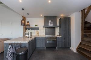 a kitchen with gray cabinets and a counter top at Welcome in - Vakantiehuis 't Zwartje met ruime tuin I Lepelstraat 18B in Vrouwenpolder +88 photos
