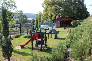 un parque con parque infantil con mesa y sillas en Penzion Ječmínek, en Červená Voda