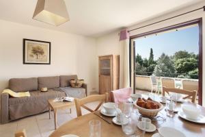 a living room with a table and a couch at Résidence Odalys Les 4 soleils in Bonnieux