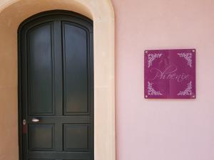 een roze muur met een zwarte deur en een paars bord bij villa Bismarkia in Siracusa
