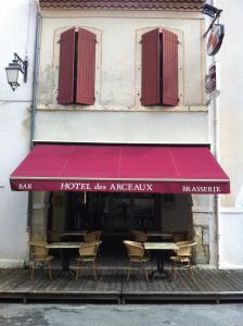 un restaurant avec un auvent rouge sur un bâtiment dans l'établissement Hotel Les Arceaux, à Saint-Sever