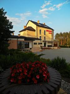 a building with a bunch of flowers in front of it at Hotel Arkadia in Ciechanowiec