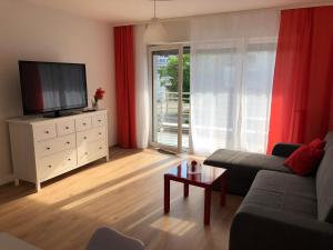 salon z kanapą i telewizorem w obiekcie Apartament W KWIATKI:) Pogorzelica w Pogorzelicy