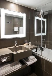 a bathroom with a sink and a mirror at Novotel Brussels Airport in Diegem