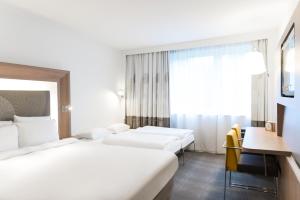 
a hotel room with a white bed and white walls at Novotel Brussels Airport in Diegem
