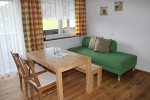 a living room with a table and a green couch at Bauernhof Strumegg in Hof bei Salzburg