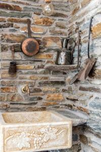 a stone wall with a stone sink and utensils at Porto Bello Tinos in Agios Ioannis