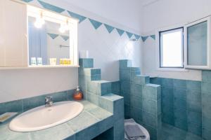 a blue tiled bathroom with a sink and a window at Porto Bello Tinos in Agios Ioannis