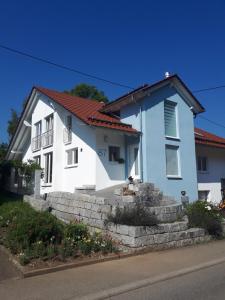 Casa azul y blanca con pared de piedra en Ferienwohnung Lochenblick, en Balingen