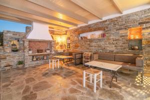 a room with a stone wall with tables and chairs at Porto Bello Tinos in Agios Ioannis
