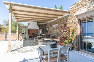 a patio with a wooden pergola and tables and chairs at Porto Bello Tinos in Agios Ioannis
