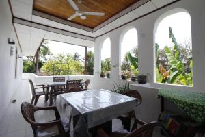 a dining room with a table and chairs and windows at Bentota Home Stay in Bentota