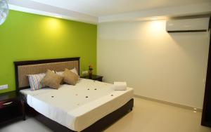 a bedroom with a large bed with green walls at Temple Plaza Kochi in Chottanikara