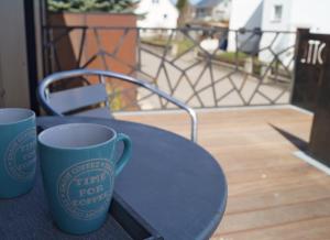 zwei blaue Kaffeetassen auf einem Tisch auf einem Balkon in der Unterkunft Alb-Lotte in Bitz
