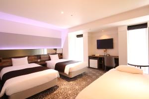 a hotel room with two beds and a flat screen tv at Quintessa Hotel Sapporo in Sapporo
