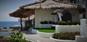 a house with a thatched roof next to the ocean at Clear View Resort in Ko Tao