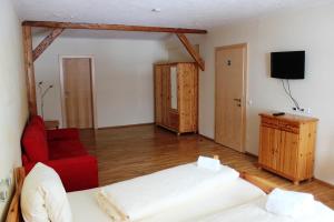 uma sala de estar com 2 camas e um sofá vermelho em Gasthof zum Goldenen Rössl em Sachsenburg