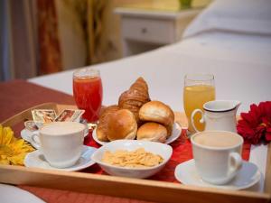 ローマにあるレジデンツァ　ドミツィアーノのベッドの上に朝食用の食品とドリンクのトレイ