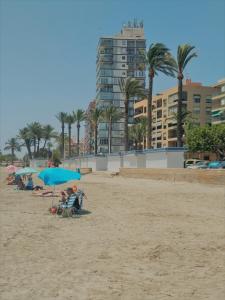 サンタ・ポラにあるApartamento a 50 metros de la playa en Santa Polaの浜辺の傘下に座る人々