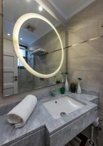 a bathroom with a sink and a round mirror at Sodic Westown Residence1-near Elnada hospital in ‘Izbat Yūsif Barrādah