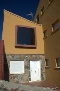 un bâtiment jaune avec une porte blanche et une fenêtre dans l'établissement Casa Rural Dunas, à Santa María de la Alameda