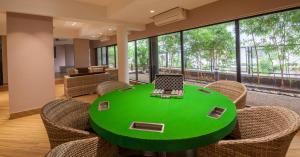 una mesa verde con sillas y un ordenador portátil. en Villa 41 by StayVista - A chic retreat with a pool, poker table, and a theater room, en Lonavala