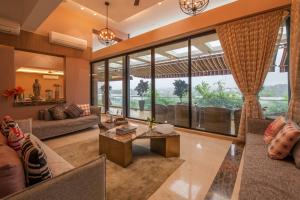 ロナバラにあるVilla 41 by StayVista - A chic retreat with a pool, poker table, and a theater roomのリビングルーム(家具付)、大きな窓が備わります。 +18枚の写真