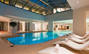 a hotel pool with white chairs and a blue swimming pool at Porto Platanias Beach Resort & Spa in Plataniás
