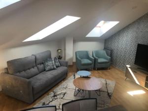a living room with a couch and chairs and a television at Ático Jaca Ciudadela in Jaca