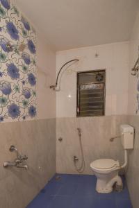 a bathroom with a toilet and a window at Hotel Om Palace in Lonavala